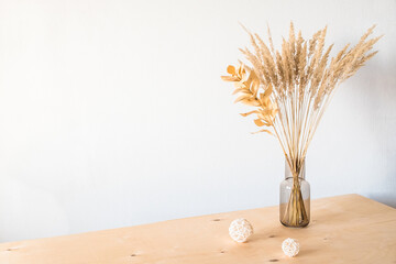 Dried flowers in a glass vase with an empty light wall for minimalist decor.