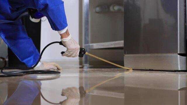 A man in a protective suit, respirator, goggles and gloves disinfects everything in the kitchen