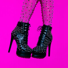 Fashion legs in heel black boots on pink  minimal background. Stylish accessories shoes concept
