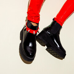 Fashion legs in platform party boots and red leather leggins on minimal background. Stylish...