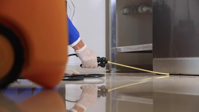 A man in a protective suit, respirator, goggles and gloves disinfects everything in the kitchen