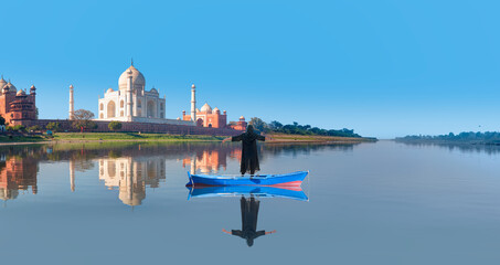 Young girl in traditional black dress raised her arms, Panoramic view of Taj Mahal in the...