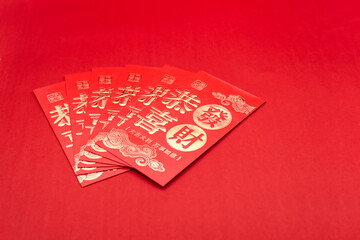A stack of Chinese New Year red envelopes on a red background