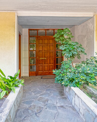 contemporary house entrance, natural wood door and green foliage plant.
