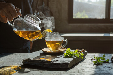 Cup of hot tea  dry tea leaves with steam and mint herb.