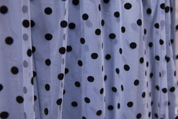 Blue mesh tulle fabric with black velvet polka dots. A skirt on a hanger in a store, photographed up close.