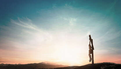 Silhouette Jesus Christ on holy cross against mountain sunset background