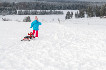 Kleinkind zieht Lenkschlitten im Schnee.
