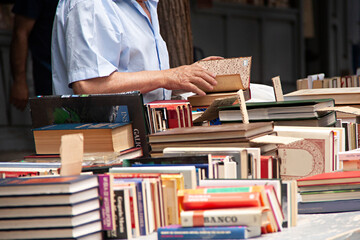 Anciano mirando un libro en puesto callejero.