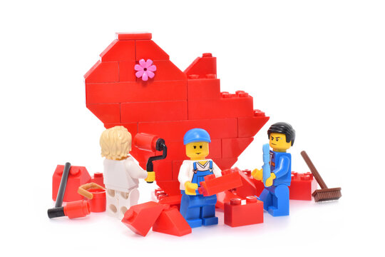 Red Heart Is Builded From Plastic Toy Bricks Isolated On White. Editorial Illustrative Image With Workers.