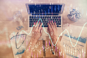 Double exposure of woman hands working on computer and forex graph hologram drawing. Top View. Financial analysis concept.