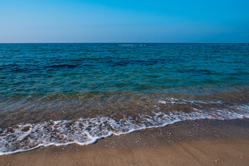 Seascape. Waves running on the sandy shore. Shore of the sea or ocean on a nice day. Vacation and relaxation by the sea.