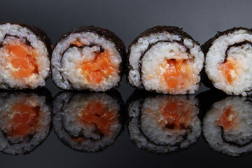 row of fresh delicious sushi rolls on a mirrored surface