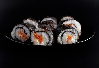 chopstick holding a sushi roll on a black background