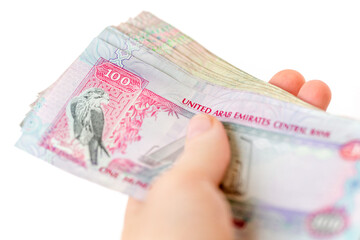 UAE dirhams in hands, stack of one hundred bills isolated on white background
