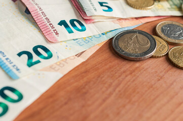 Fan of euro banknotes and some coins on a wooden table