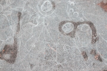 Cracked ice on concrete with yellow leaves. Yellow leaves and concrete can be seen under the cracked ice