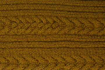 Wool knitted canvas in  mustard with ribs cables, hand knit, pattern, place for text. Horizontal photo