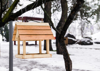 Naklejka premium Wooden bird feeder on a tree in winter. winter, forest landscape at sunset. bird feeders