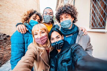 Multiracial friends covered by face mask taking selfie wearing winter clothes - New normal...