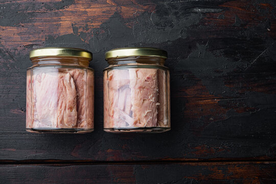 Jar of tuna in olive oil, on old wooden table, top view  with copy space for text