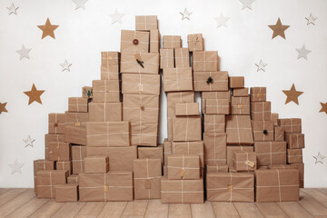 Big stack with paper vintage gift boxes on the wooden floor decorated with star on the white wall.
