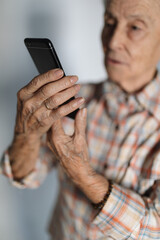 Hands of an elderly person using a smartphone. Technology concept.