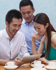 Three people sit together working on a tablet