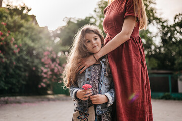 daughter in the arms of her mother in the park with a flower in her hands. Support for parents of...