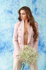 Portrait of a confident young woman in a pink jacket, holding a bouquet of gypsophila.