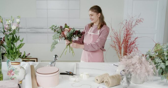 Happy woman florist small business owner flower shop creates a new flower arrangement for shoppers