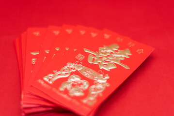 A stack of Chinese New Year red envelopes on a red background