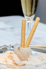 Handmade ice cream with wafers on a white background. Vertical. Tangerine ice cream and banana-rum-raisin ice cream. Glass of champagne