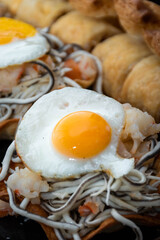 Vertical and zenithal macro view of puff pastry with gluttony, quail egg and prawns with unfocused background.