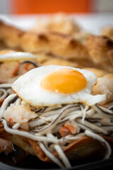 Vertical macro view of puff pastry with gluttony, quail egg and prawns with an unfocused background.