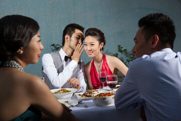 Four people sit together for dinner and chat