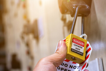 Hand holding yellow key lock and tag for process cut off electrical,the toggle tags number for...