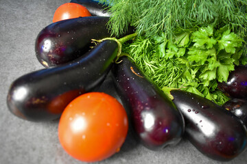Ripe eggplants, juicy tomatoes and parsley and dill on the table