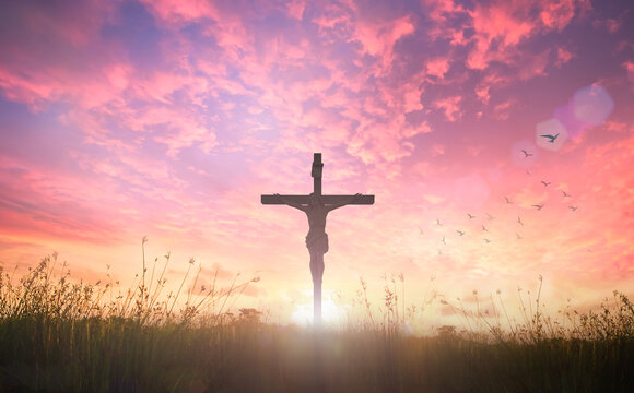 Silhouette Jesus Christ on the cross against meadow sunrise background