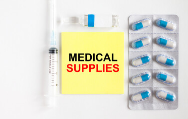 Yellow sticker with text Medical Supplies on a white background with syringes, pills and ampoule.