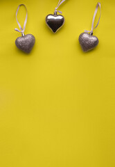 three silver hearts on a yellow background. Valentine's day card. Valentine's day flat lay. Copy space. St. Valentine's Day. Colors of 2021.