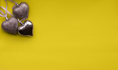 three silver hearts on a yellow background. Valentine's day card. Valentine's day flat lay. Copy space. St. Valentine's Day. Colors of 2021.