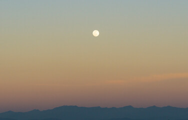 scenic picture of the moon at the dusk in the sky over mountain
