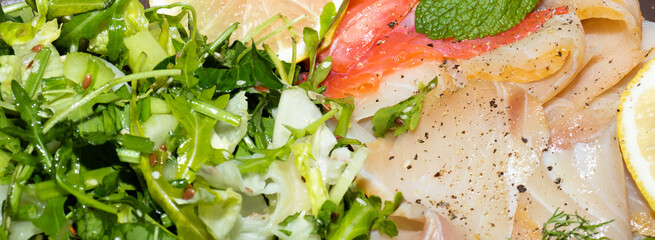Slices fish and green salad background. Tasty and healthy sashimi close-up.