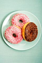 three donuts or doughnuts on aquamarine plate in simple graphic style