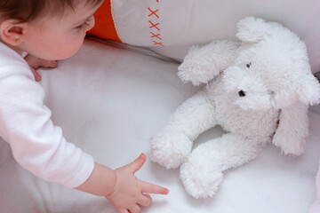 baby reaches out for a teddy bear