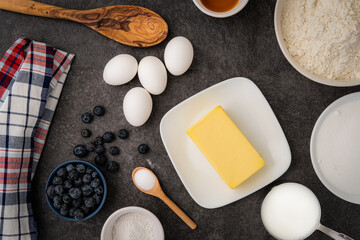 A display of both the wet and dry ingrediants needed to make blueberry muffins on the kitchen counter