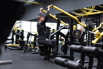 A healthy, fit bodybuilder is exercising with equipment in the gym. Daily trening.