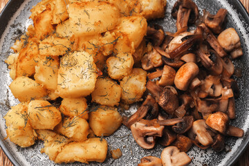 Close-up, top view of fried mushrooms and potatoes on a gray concrete plat