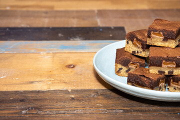 A plate of delicious chocolate brownies on a wooden kitchen work top, tasty deserts in a pile ready to be eaten